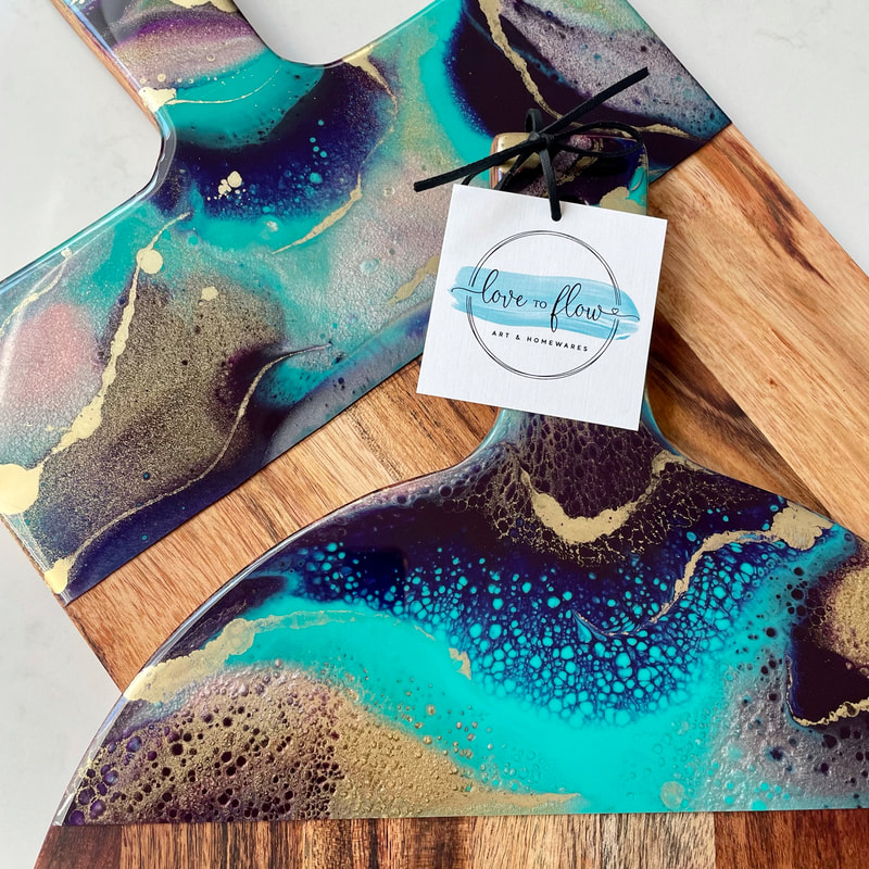 two resin art cheese boards with bright abstract resin art on them.